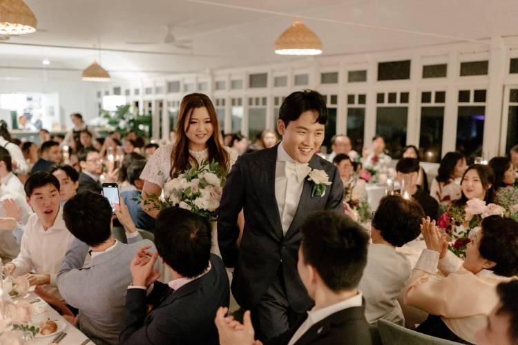 Bride & groom walking through wedding reception organised by event planner